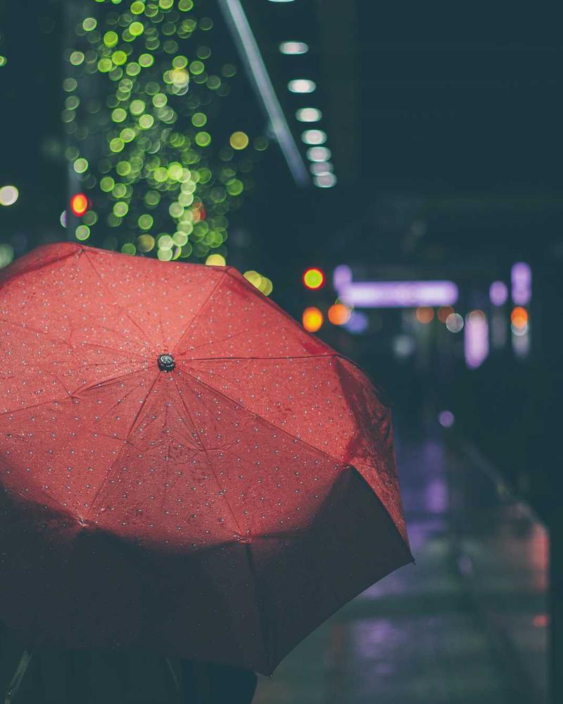 A red umbrella in the rain at night